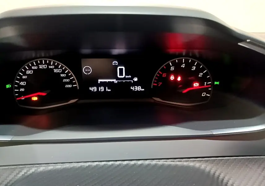 Vue rapprochée du tableau de bord numérique de la Peugeot 208 blanc, affichant la vitesse à 0 km/h et le compteur kilométrique.