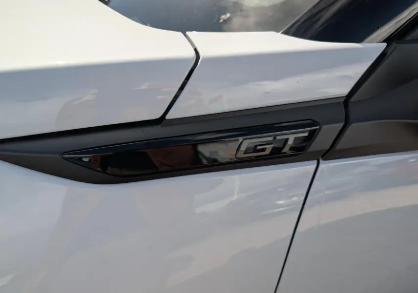 Gros plan sur l’inscription GT noire brillante sur la porte blanche côté droit du Peugeot 2008 hybride.