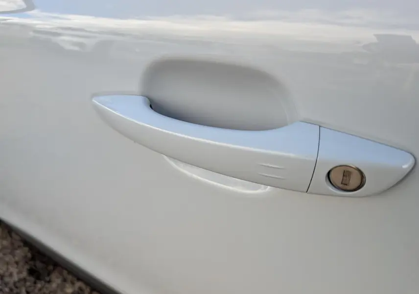 Poignée de porte blanche côté gauche du Peugeot 2008 1.2i Hybrid GT 2026, avec serrure intégrée visible.