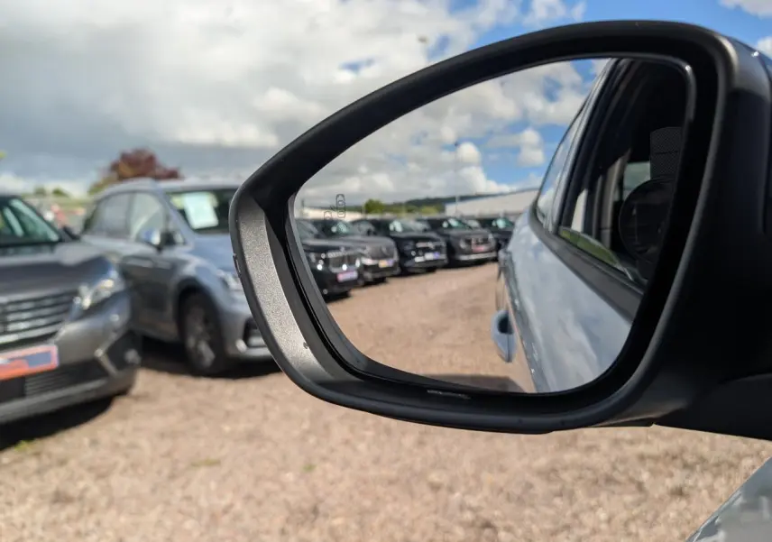 Rétroviseur droit d'une Peugeot 2008 blanche GT hybride, avec vue sur plusieurs véhicules en arrière-plan.