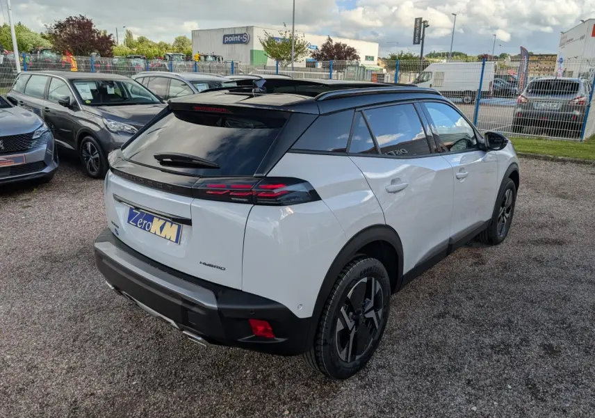 Vue 3/4 arrière droite du Peugeot 2008 blanc avec toit noir brillant et jantes alliage bi-ton.