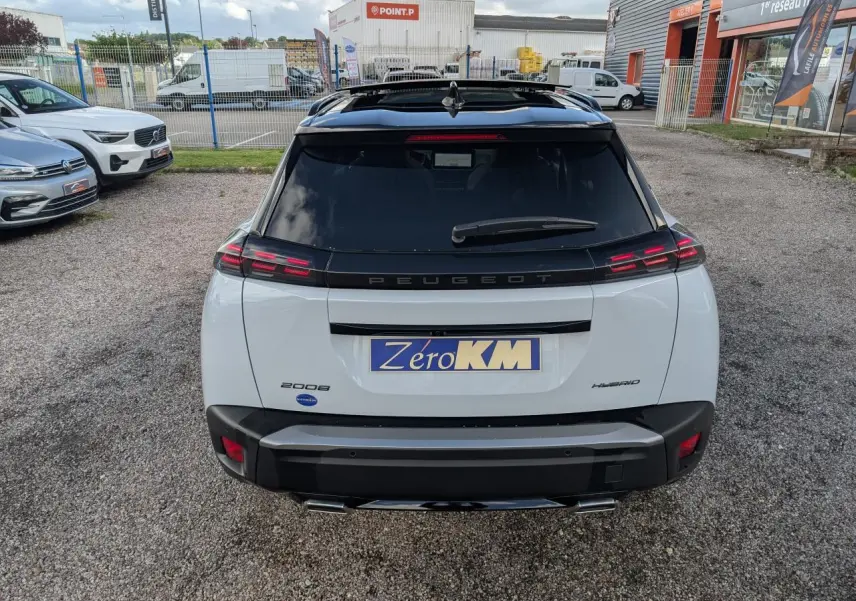 Vue arrière d’un Peugeot 2008 blanc hybride avec toit noir et feux arrière LED distinctifs en griffes.