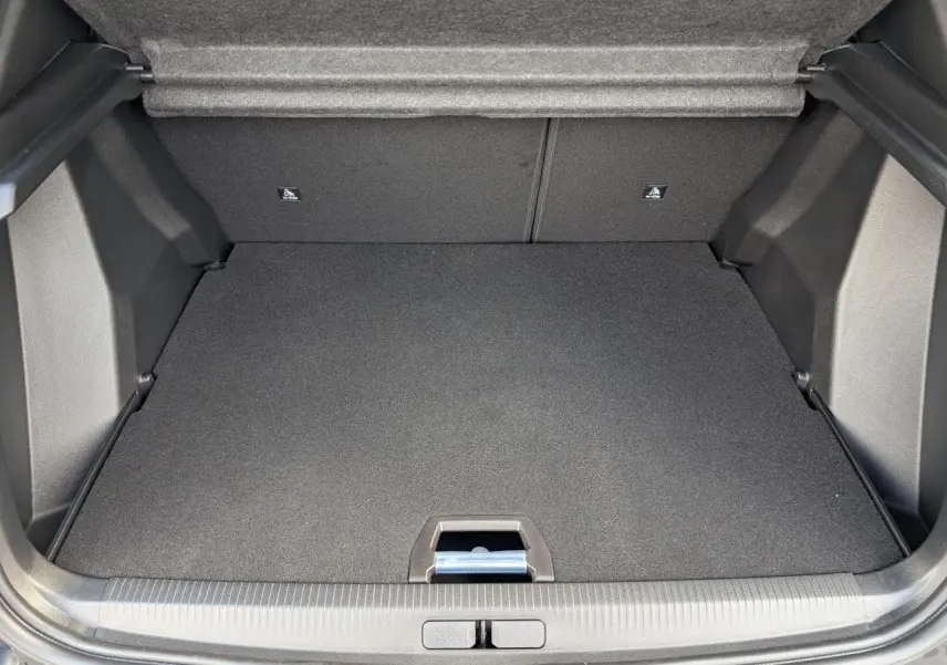 Coffre ouvert du Peugeot 2008 blanc, montrant le plancher plat et la moquette noire intérieure.
