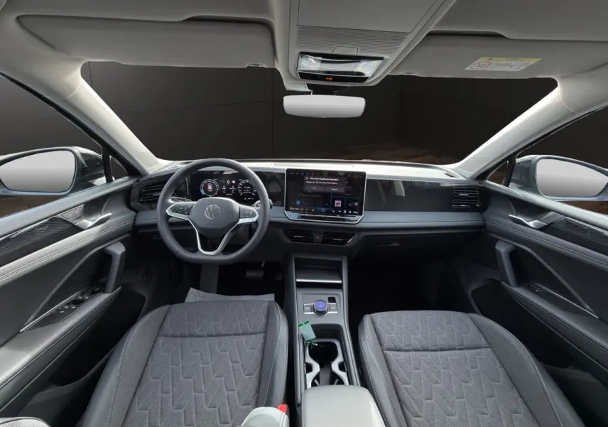 Vue intérieure avant du Volkswagen Tiguan 2026, tableau de bord moderne avec écran tactile central et sièges gris.