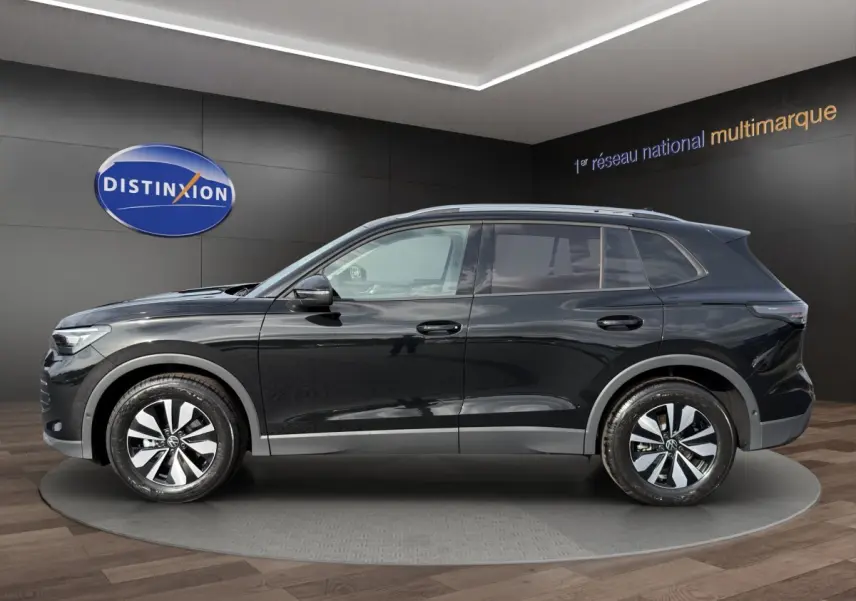 Profil côté gauche du Volkswagen Tiguan noir 2026 avec jantes alliage et rails de toit noirs en showroom.