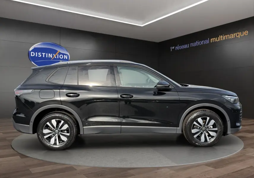 Volkswagen Tiguan noir vue de profil côté gauche, avec jantes modernes et lignes épurées en intérieur showroom.