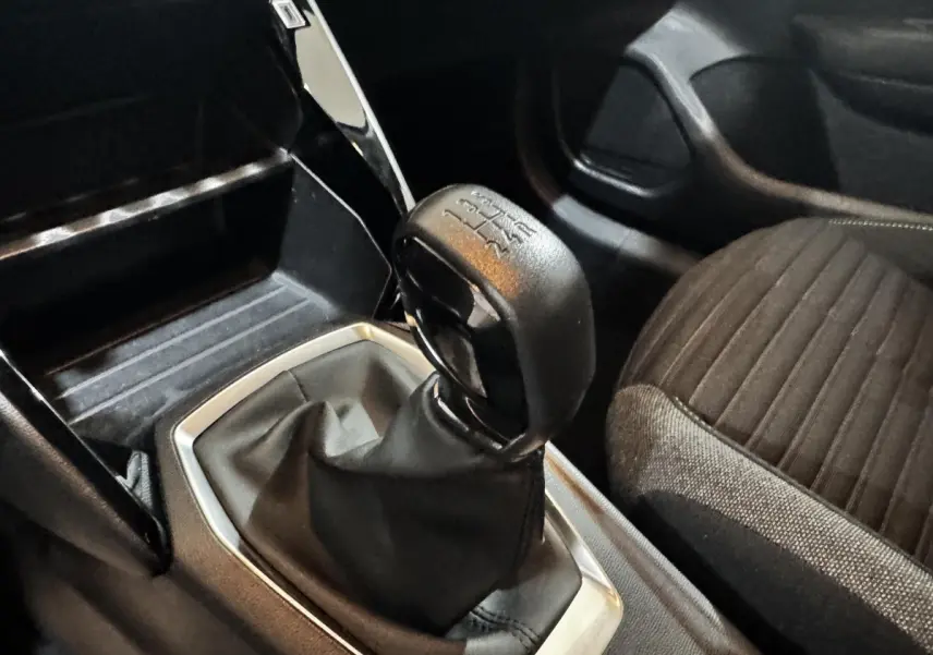 Gros plan sur le levier de vitesse manuel et la console centrale noire à l'intérieur d'une Peugeot 208 blanche.