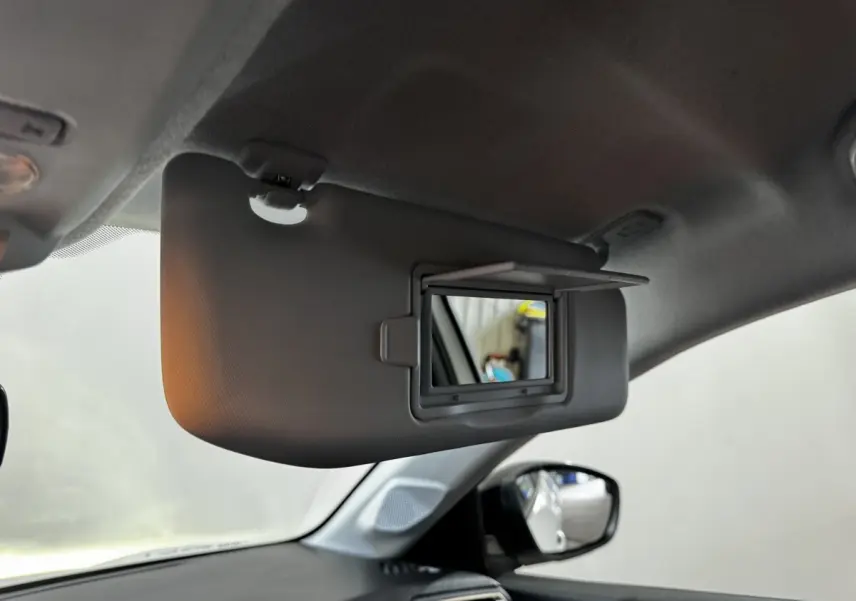 Miroir de courtoisie ouvert sur pare-soleil côté conducteur dans l'habitacle d'une Peugeot 208 blanche.
