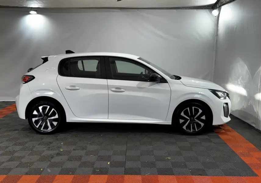 Profil droit de la Peugeot 208 blanche 2024 PureTech 75 S&S Active avec jantes noires et phares LED visibles.