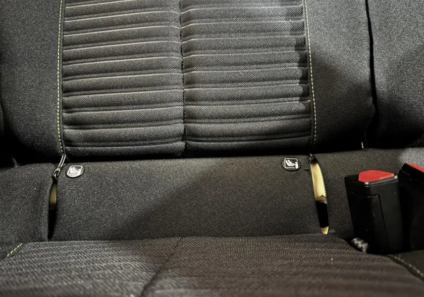 Gros plan sur la banquette arrière noire du Peugeot 208 PureTech 75 S&S Active avec coutures vertes et attaches Isofix visibles.