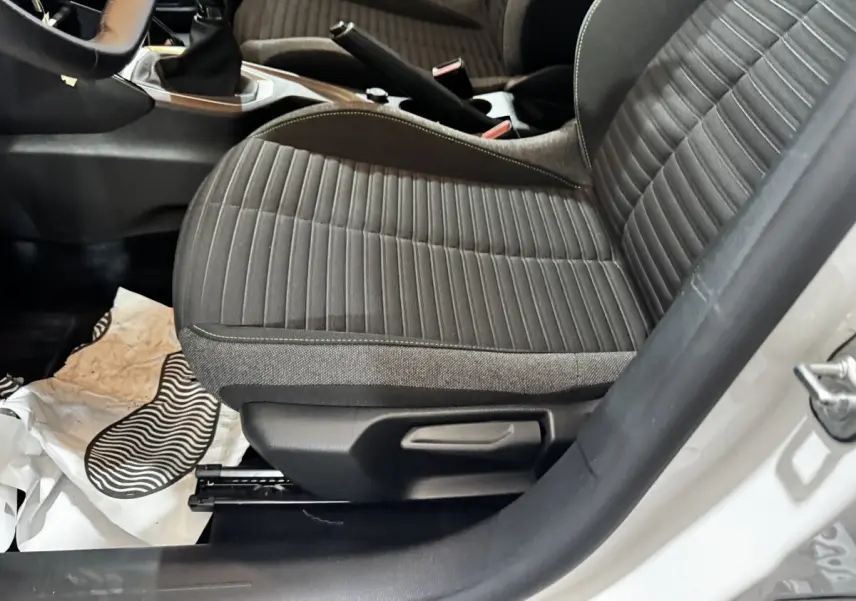 Vue rapprochée du siège avant droit gris à coutures vertes dans l’habitacle d’une Peugeot 208 blanche.