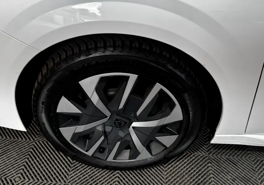 Gros plan sur la roue arrière droite blanche d'une Peugeot 208 PureTech 75 S&S Active avec jante au design moderne.