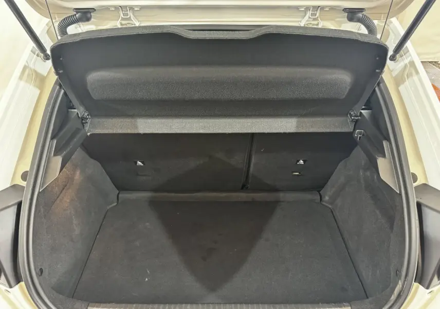 Coffre ouvert vu de face d'une Peugeot 208 blanche, montrant l'espace de chargement vide et la tablette arrière.