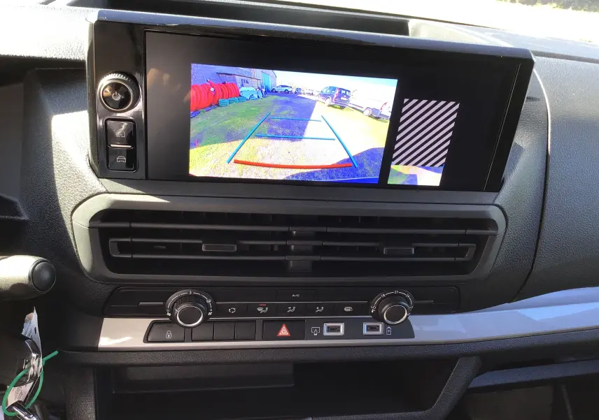 Gros plan sur les commandes du volant côté gauche du Peugeot Expert XL gris titane, avec tableau de bord numérique en arrière-plan.