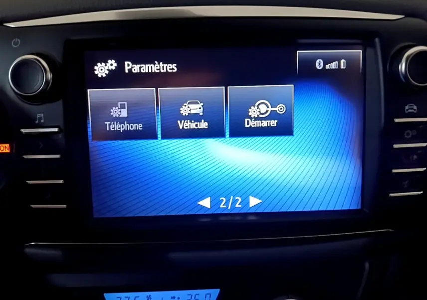 Écran tactile central affichant les paramètres du véhicule Toyota Yaris hybride blanc, vue intérieure frontale.