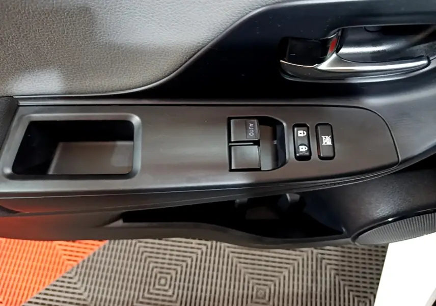 Gros plan sur la commande des vitres et verrouillage côté conducteur de la porte noire intérieure d'une Toyota Yaris blanche 2019.