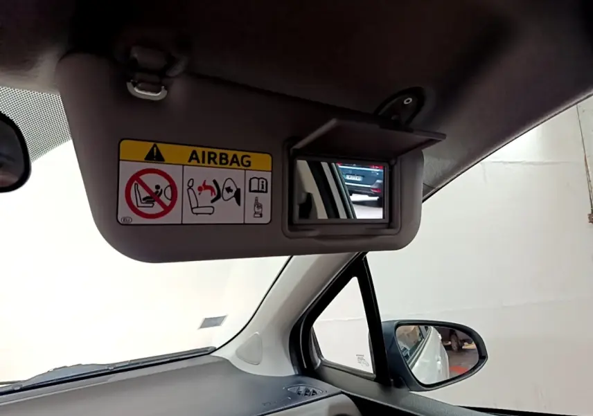 Détail du pare-soleil côté conducteur avec miroir et avertissement airbag dans l'habitacle d'une Toyota Yaris blanche 2019.