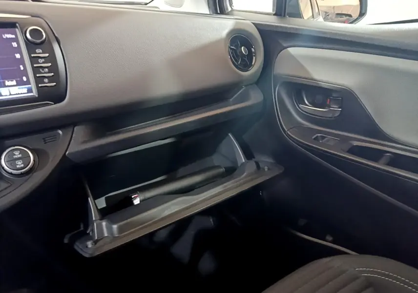 Intérieur côté passager de la Toyota Yaris blanche 2019, avec boîte à gants ouverte et tableau de bord noir.