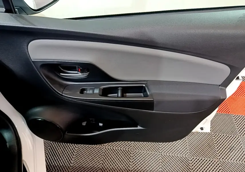 Gros plan sur la porte avant gauche blanche d'une Toyota Yaris 2019, avec panneau intérieur noir et gris.