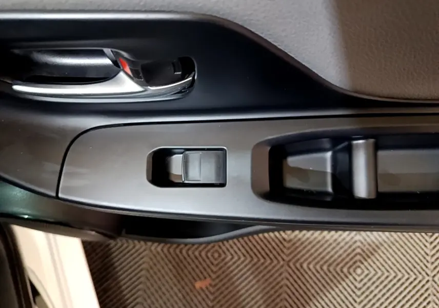 Vue rapprochée de la poignée intérieure et des commandes de la porte côté conducteur d'une Toyota Yaris blanche.