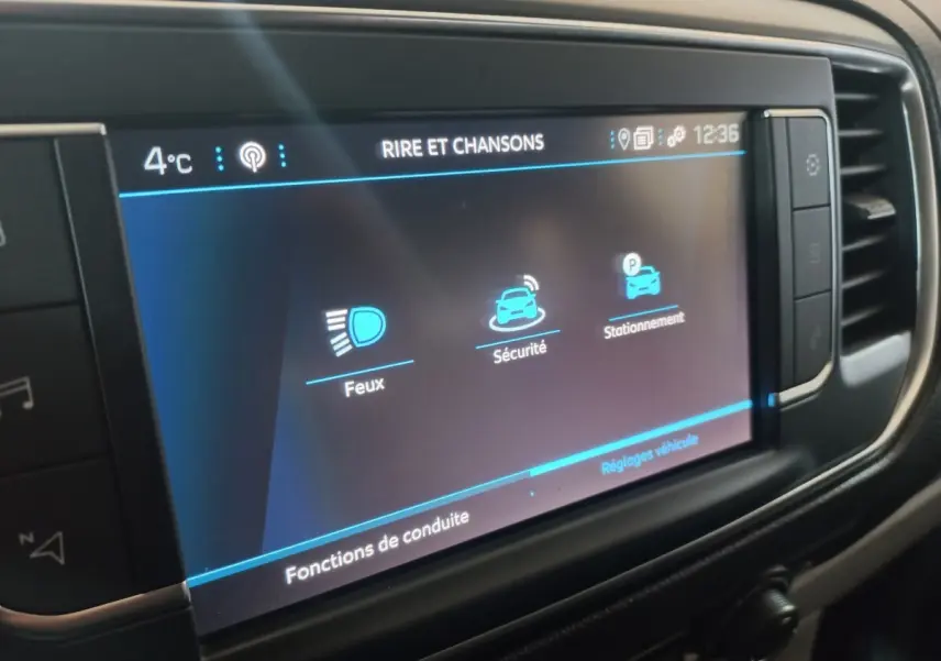 Écran tactile central du Peugeot Traveller gris clair, affichant les réglages de conduite et sécurité.