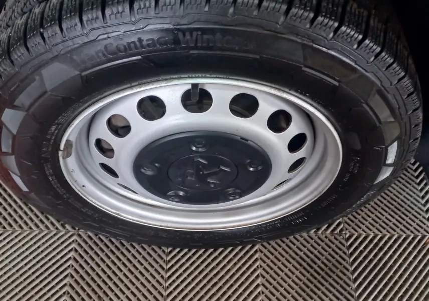 Gros plan sur la roue acier avec logo Peugeot d’un Peugeot Traveller gris clair, vue de profil côté droit.