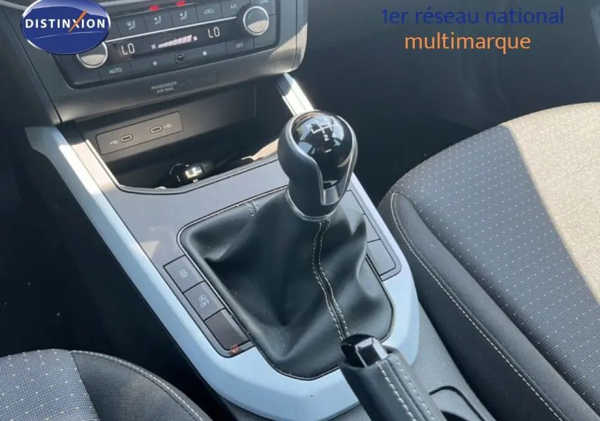 Gros plan sur la console centrale du SEAT Arona 2025, boîte manuelle avec levier de vitesses et sièges tissu gris.