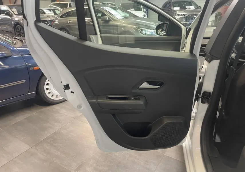 Vue intérieure de la porte arrière droite noire d'une Dacia Sandero blanche 2024 avec poignée argentée.