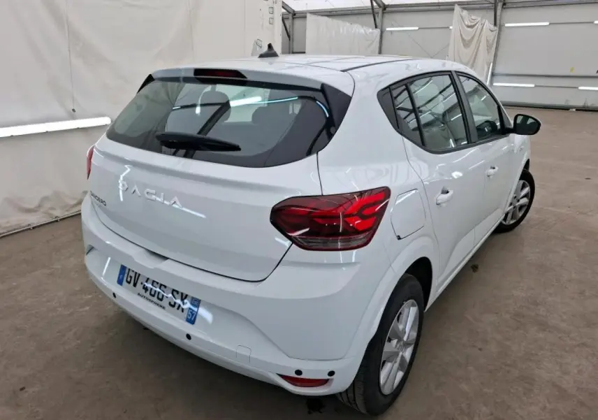 Vue 3/4 arrière droite d'une Dacia Sandero blanche 2024 avec feux arrière LED et jantes à enjoliveurs.