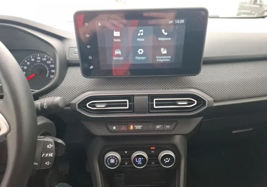 Vue intérieure du tableau de bord de la Dacia Sandero 2024 avec écran tactile et commandes de climatisation.