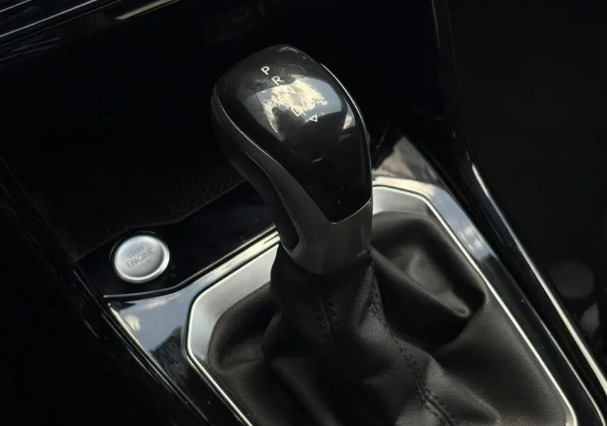 Le levier de vitesse automatique noir du Volkswagen T-Roc 2025 en gros plan avec bouton Start/Stop adjacent.