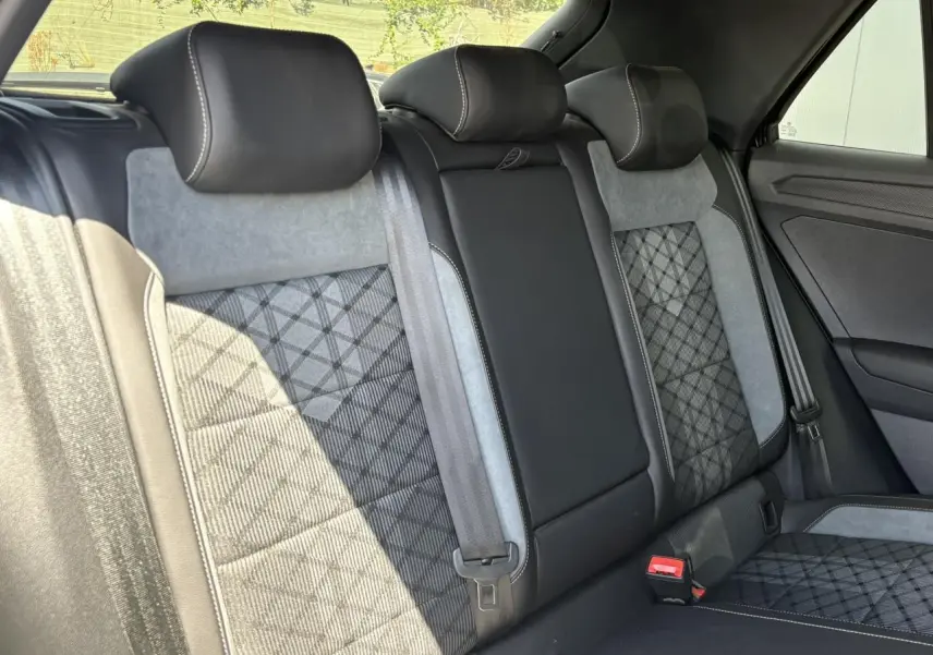 Vue intérieure arrière du Volkswagen T-Roc 2025 montrant les sièges cuir et alcantara gris et noirs avec surpiqûres contrastantes.