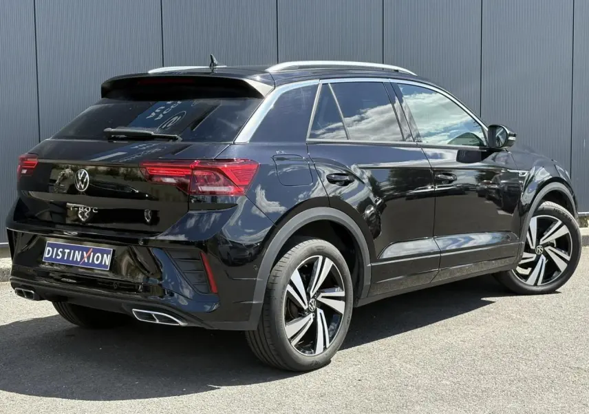 Vue 3/4 arrière droite d’un Volkswagen T-Roc noir intense avec jantes alliage 18 pouces et finitions R-Line visibles.