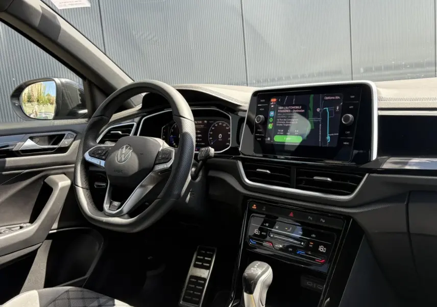 Intérieur du Volkswagen T-Roc 1.5 TSI 2025 vu côté conducteur, volant cuir R-Line et écran tactile central allumé.