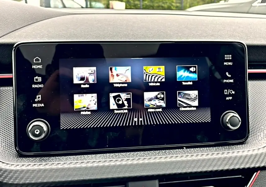 Écran tactile central du tableau de bord du Skoda Kamiq blanc nacré, avec interface multimédia et commandes autour.
