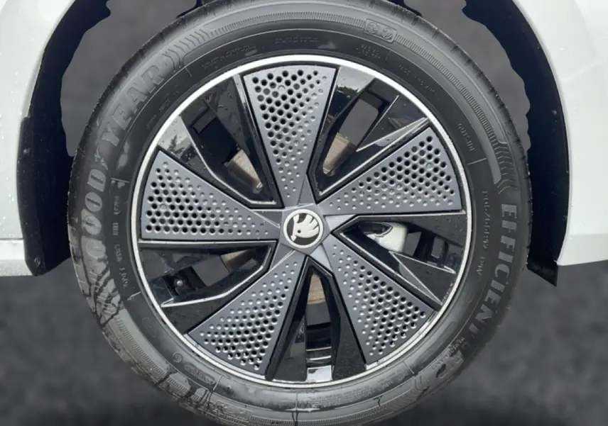 Gros plan sur la jante noire et grise du Skoda Kamiq blanc nacré, avec logo central distinctif au centre.
