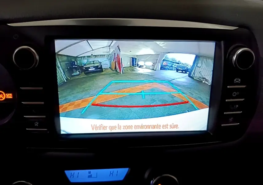 Écran de caméra de recul de la Toyota Yaris blanche, vue intérieure du tableau de bord avec guidage de stationnement.