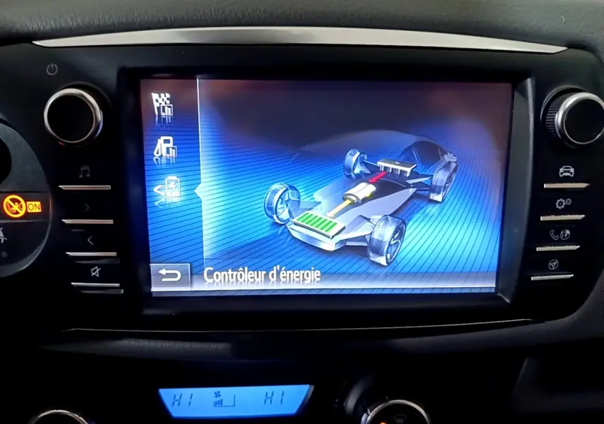 Écran tactile central affichant le contrôle d'énergie hybride dans le tableau de bord d'une Toyota Yaris blanche.