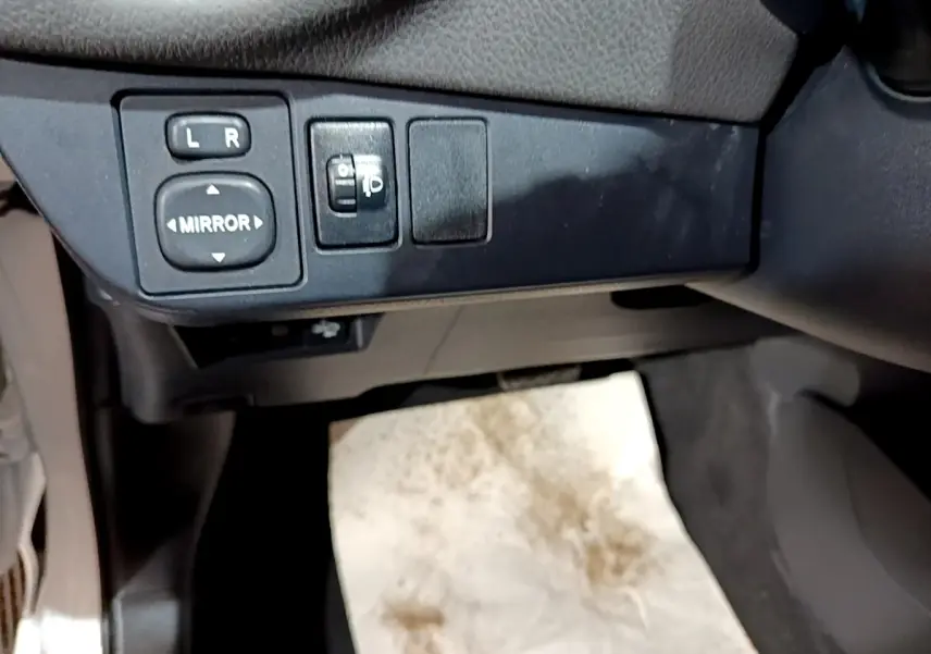 Gros plan sur les commandes de réglage des rétroviseurs côté conducteur de la Toyota Yaris blanche 2019.