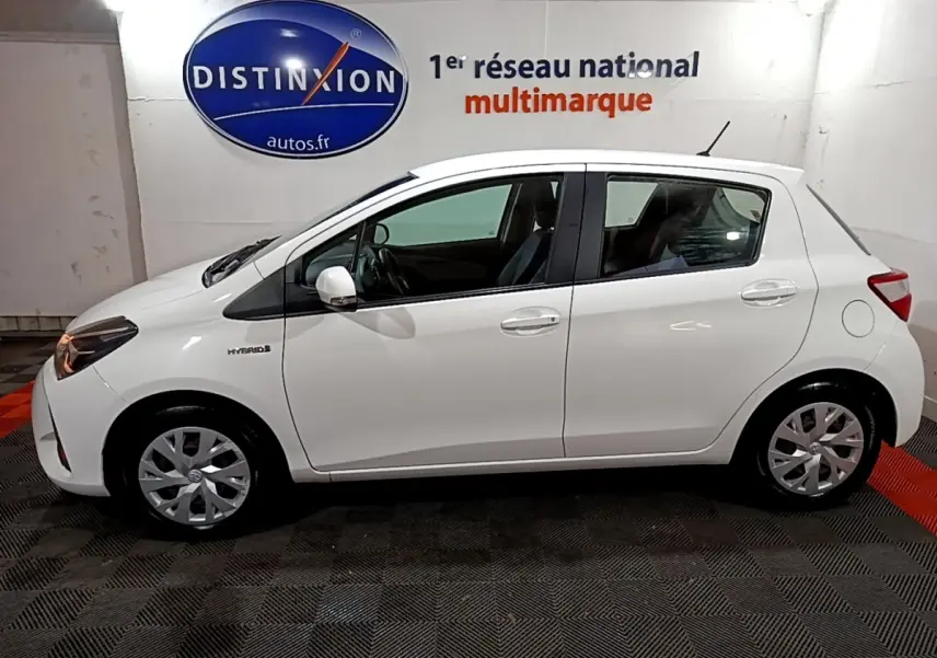 Profil côté gauche d'une Toyota Yaris blanche hybride 2019, avec logo Hybrid visible sur l'aile avant.