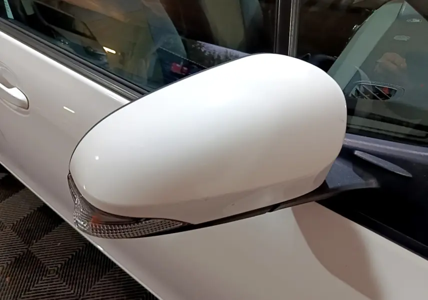 Rétroviseur côté gauche blanc de la Toyota Yaris hybride 2019, avec clignotant intégré visible en gros plan.