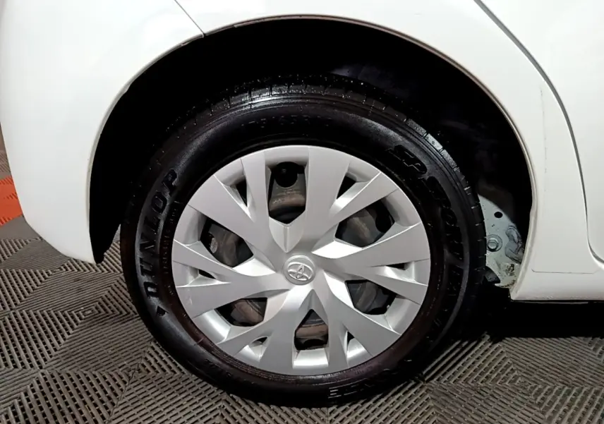 Gros plan sur la roue avant droite blanche d'une Toyota Yaris 1.5 VVT-I Hybrid avec enjoliveur argenté et pneu Dunlop.