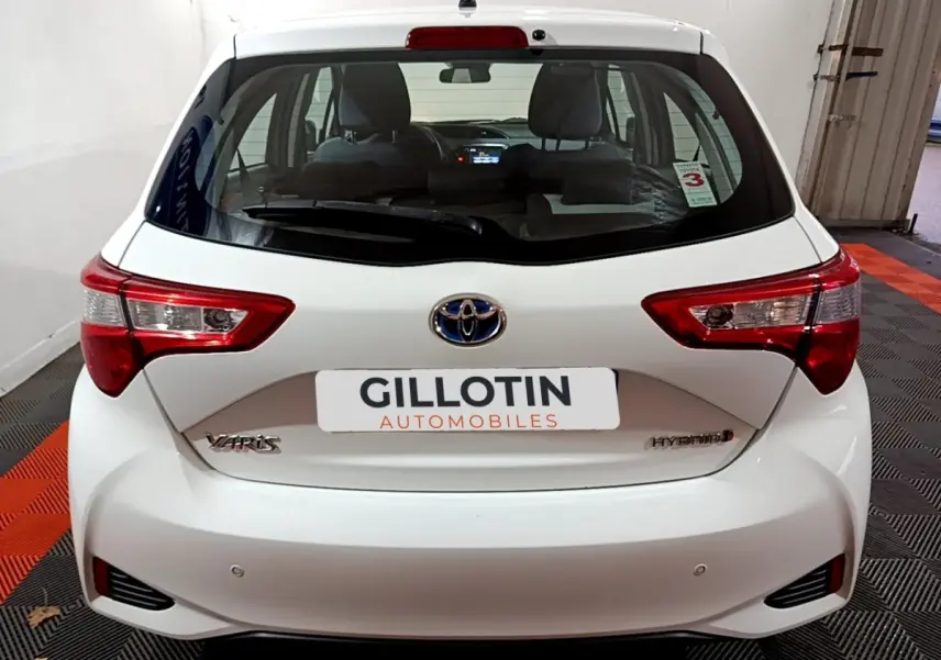 Vue arrière d'une Toyota Yaris hybride blanche 2019 avec feux arrière nets et logo Toyota centré.