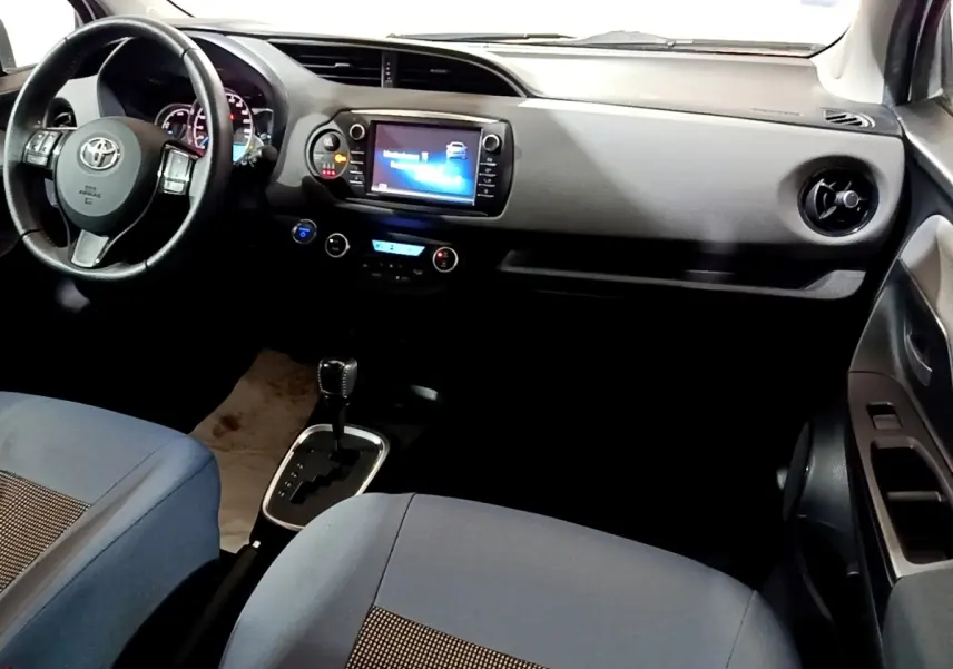 Vue intérieure avant droite de la Toyota Yaris hybride 2019 avec tableau de bord noir et écran tactile central.
