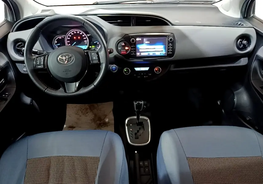 Intérieur de la Toyota Yaris hybride 2019, vue frontale du tableau de bord avec volant cuir et écran tactile central.