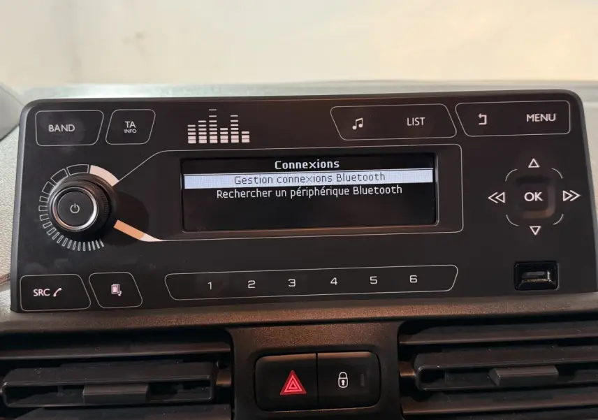 Vue rapprochée du tableau de bord du Peugeot Rifter blanc 2019, affichage Bluetooth et commandes audio visibles.