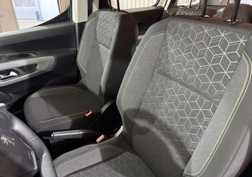 Vue intérieure rapprochée des sièges avant gris à motifs géométriques du Peugeot Rifter blanc, version PureTech 110 S&S Active.