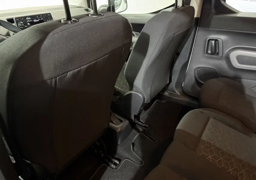 Vue intérieure arrière droite du Peugeot Rifter 2019 blanc, montrant les sièges en tissu noir et la porte latérale.