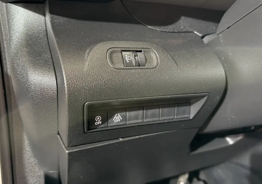 Détail du tableau de bord noir du Peugeot Rifter 2019, montrant les commandes d’éclairage et d’assistance à la conduite.