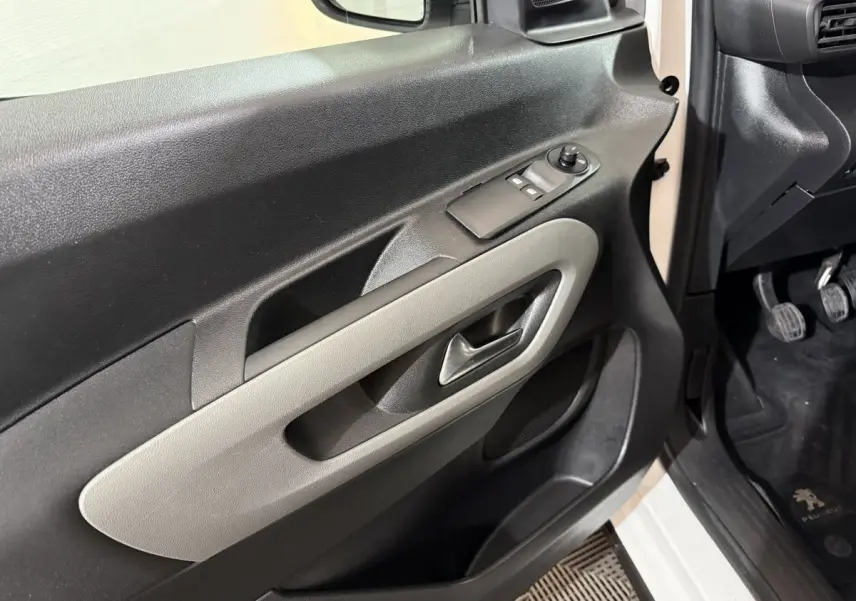 Vue rapprochée de la porte avant gauche noire et beige du Peugeot Rifter blanc, avec commandes de vitres et poignée intégrée.